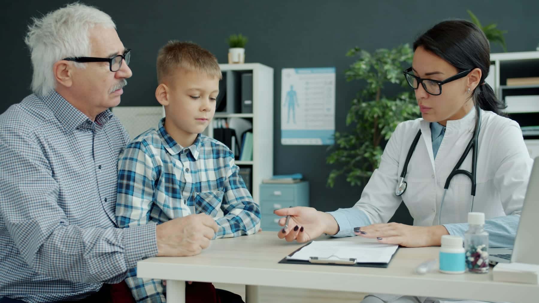 Ophthalmologist talking with a grandfather and grandson during a consultation