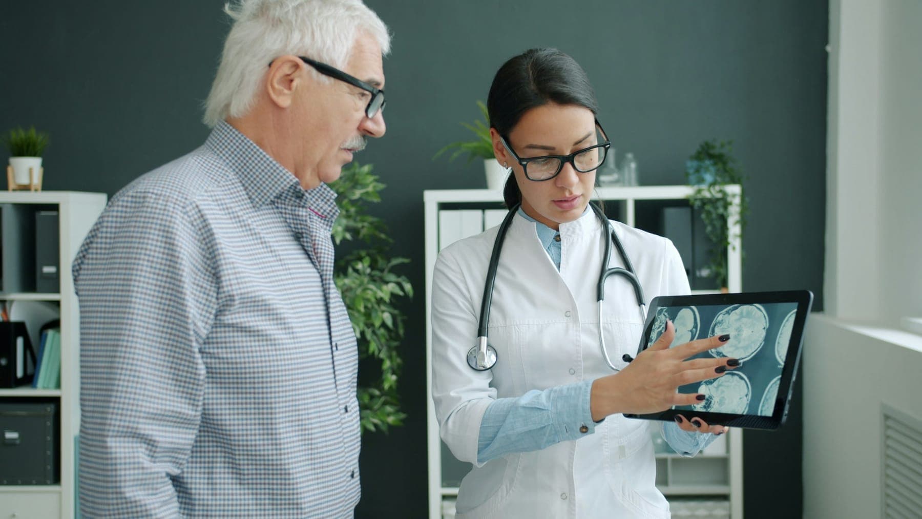 Doctor reviewing a medical scan on a tablet with a patient