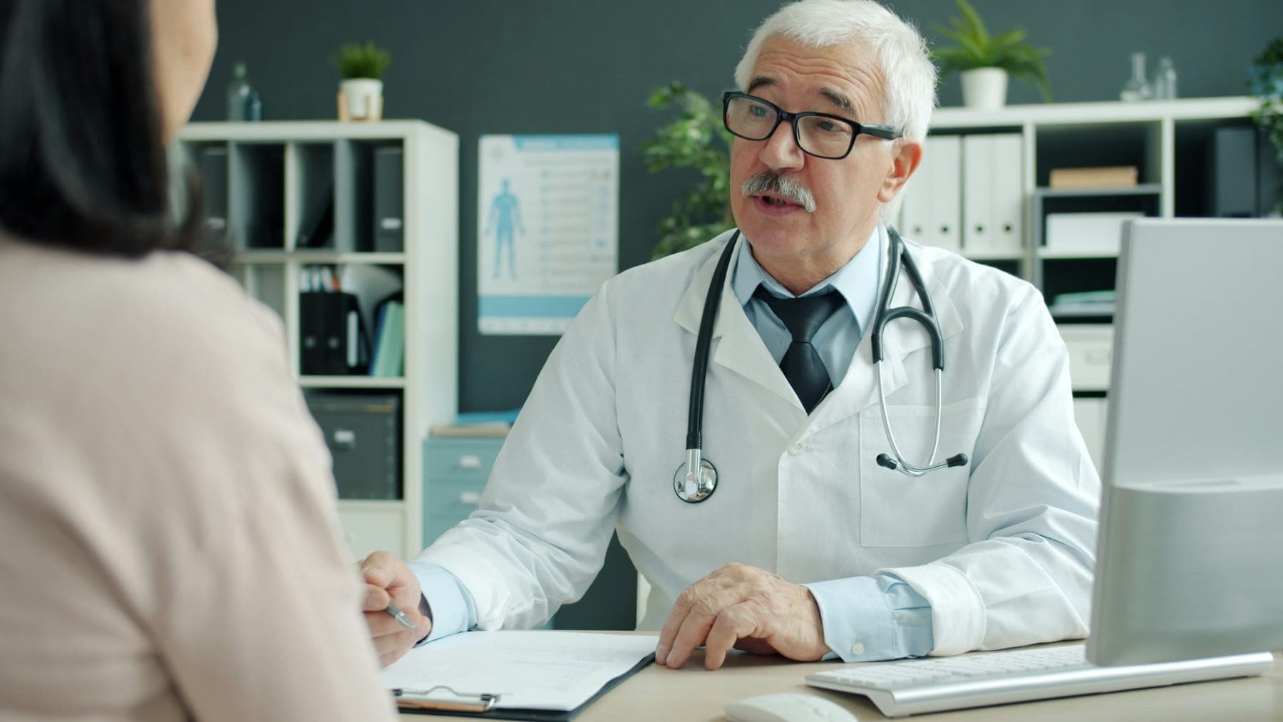 Senior ophthalmologist listening to a patient across a desk