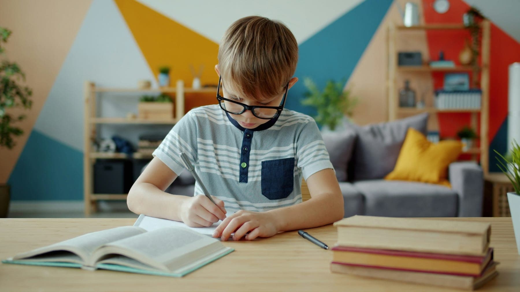 Young boy with glasses writing at a desk