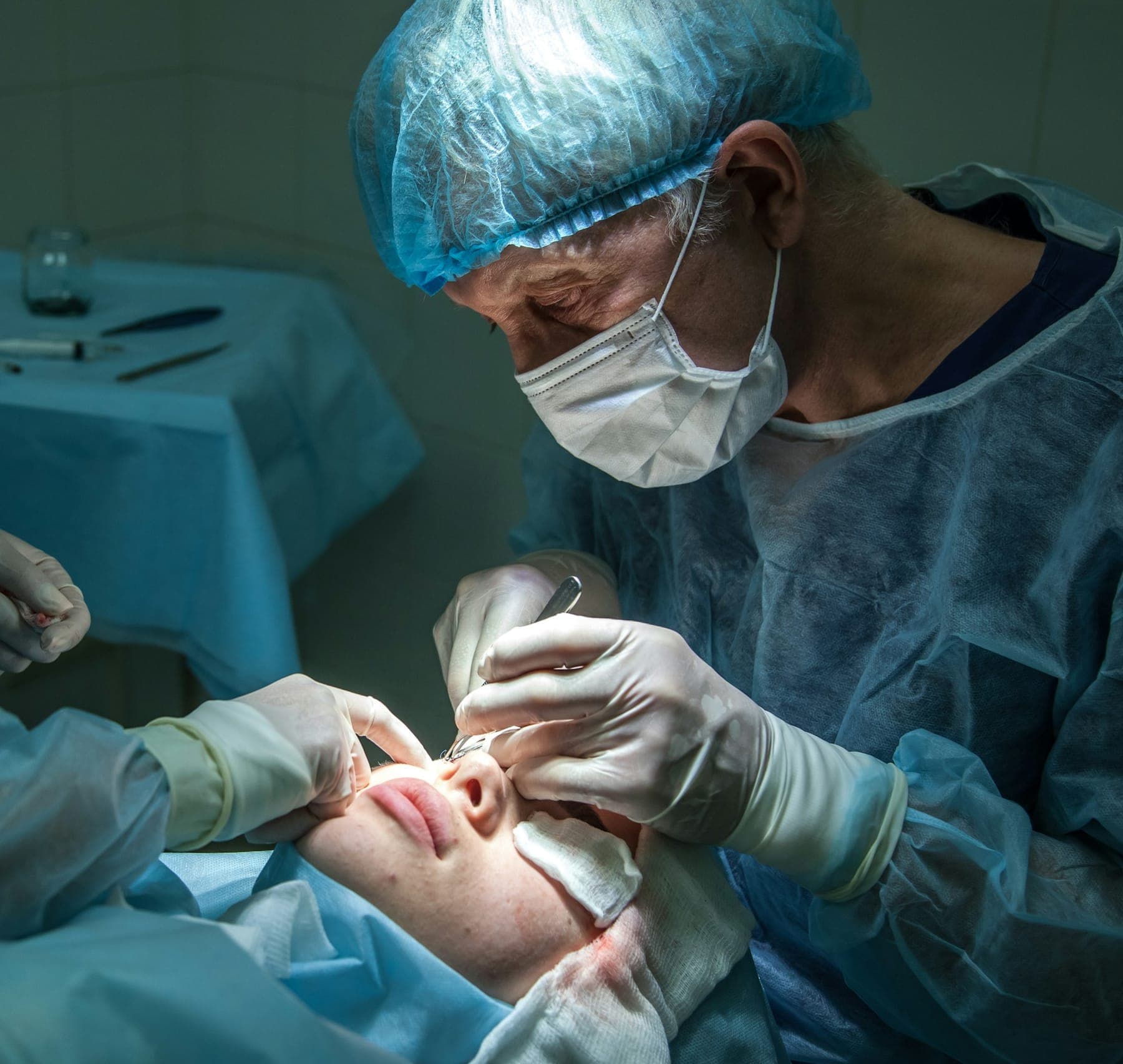 Surgeon in a cap and mask operating on a patient's eye